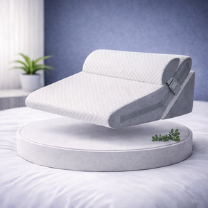 Coussin ergonomique incliné modulable avec sangle ajustable, présenté sur un socle dans une chambre moderne.
