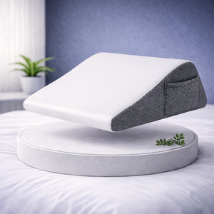 Coussin ergonomique incliné sans rouleau de soutien, présenté seul sur un socle dans une chambre moderne.