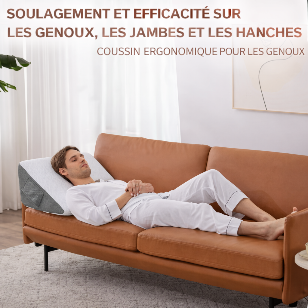 Homme allongé sur un canapé avec un coussin ergonomique incliné pour soulager les genoux, les jambes et les hanches.